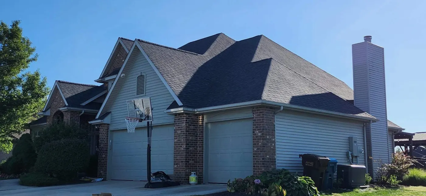 Brick home with garage and dark shingle roof
