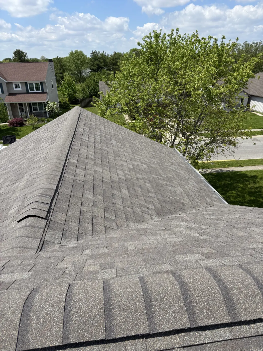 Shingled roof ridge with neighborhood view
